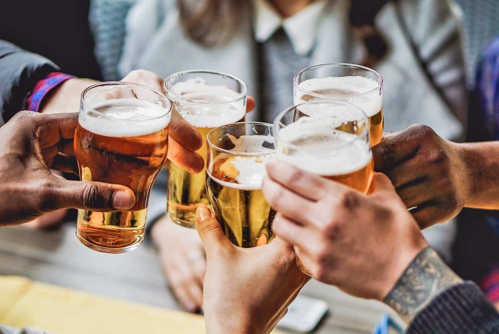 Four people cheering with glasses of beer at one of the upcoming events in San Antonio.